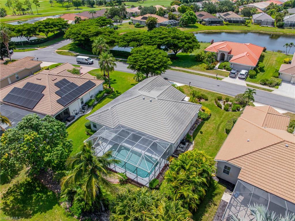 Screen-enclosed pool, mature landscaping, tile roof, and a paved driveway