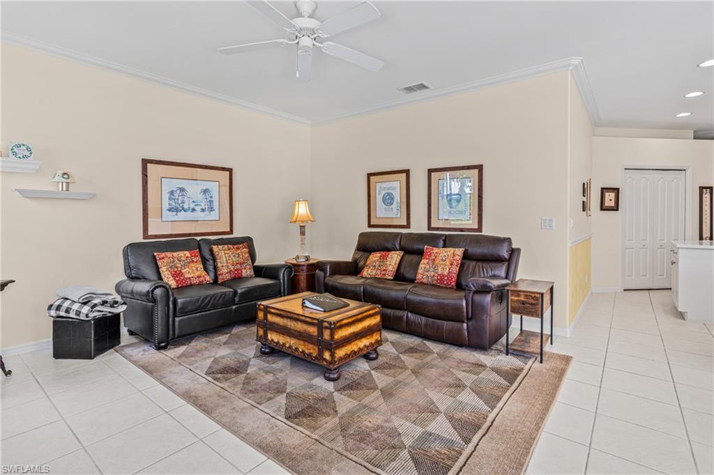 Crown molding detailing, ceiling fan with light fixture, light-toned wall finishes, white tile flooring, and white bi-fold doors