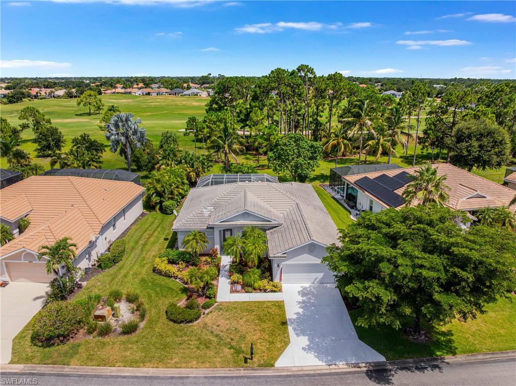Expansive golf course frontage with a screened lanai, manicured landscaping, and a paver driveway