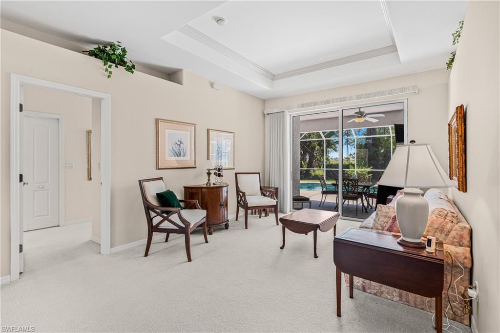 Tray ceiling with crown molding, light-colored carpeting, and sliding glass doors