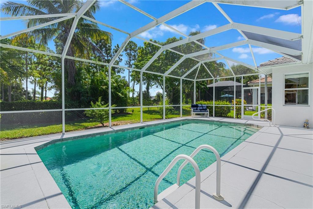 Screened outdoor pool with a tiled coping, white pool steps, and a surrounding paver deck