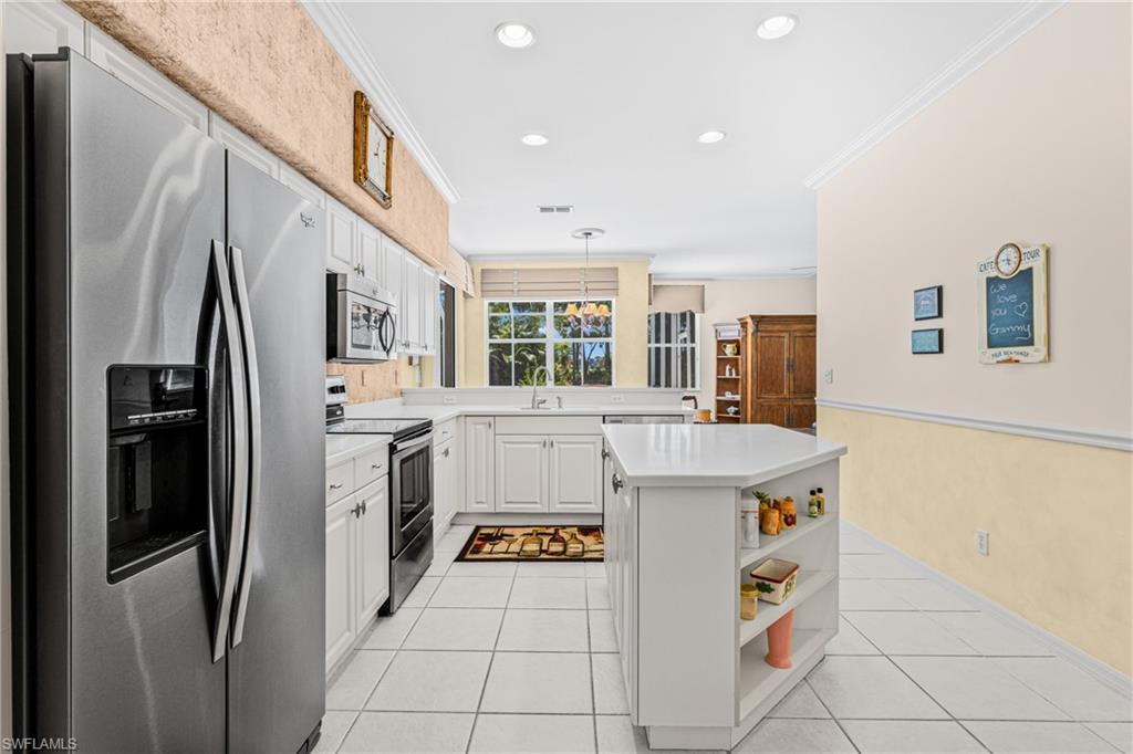White cabinetry, stainless steel appliances, central island, recessed lighting, and tile flooring