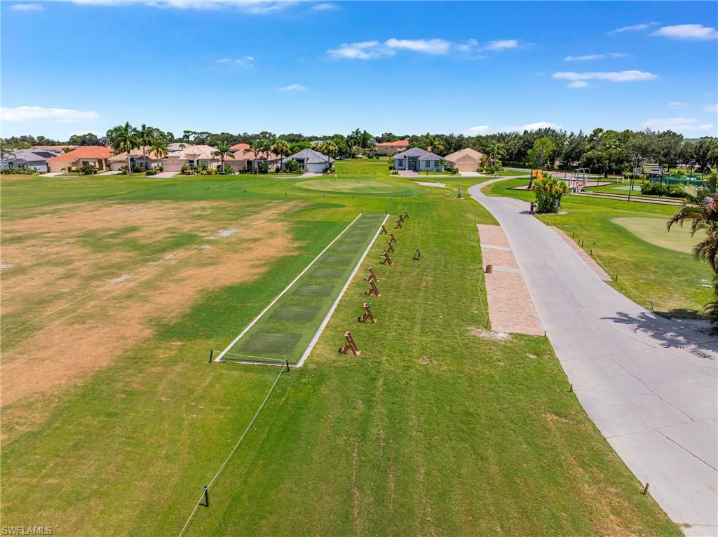 Golf course frontage with a putting green, a paved pathway, and surrounding residences
