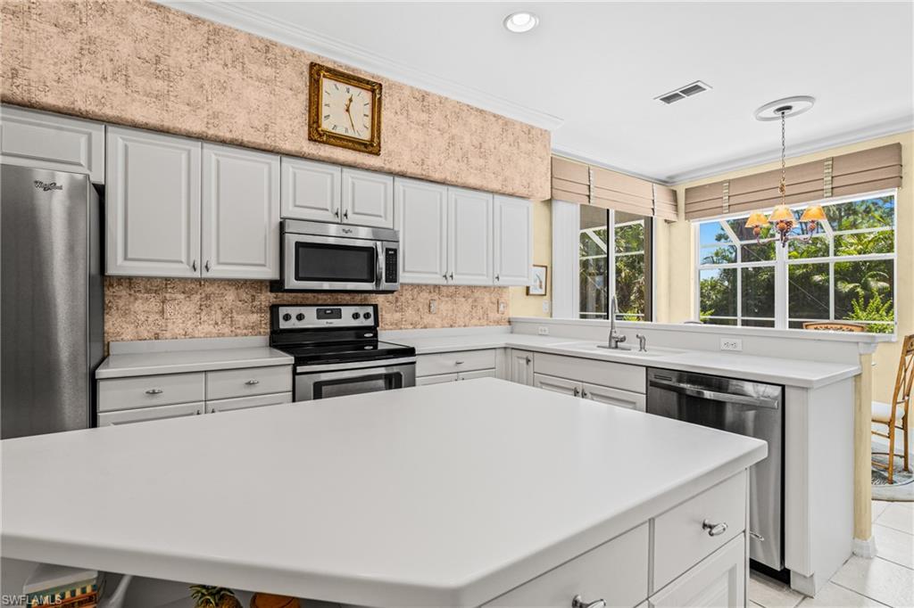 Kitchen featuring white cabinetry, stainless steel appliances, a center island, and a window overlooking exterior landscaping