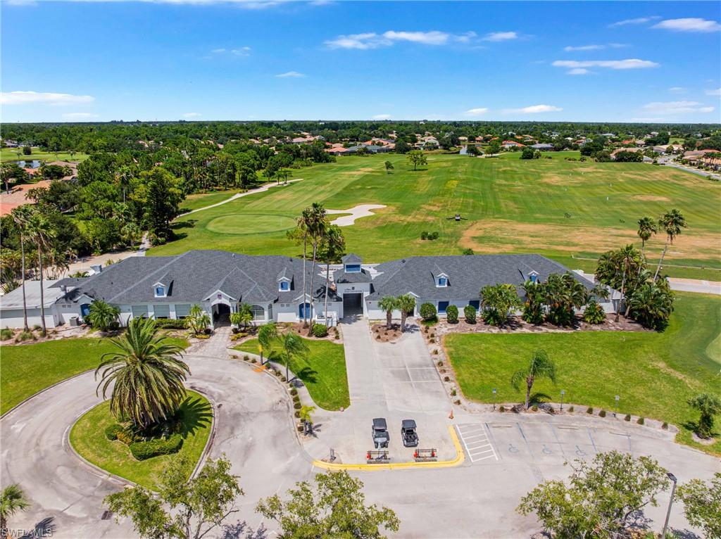 Expansive golf course backdrop, large building with multiple gables, extensive paved parking area, mature palm trees, and manicured green spaces