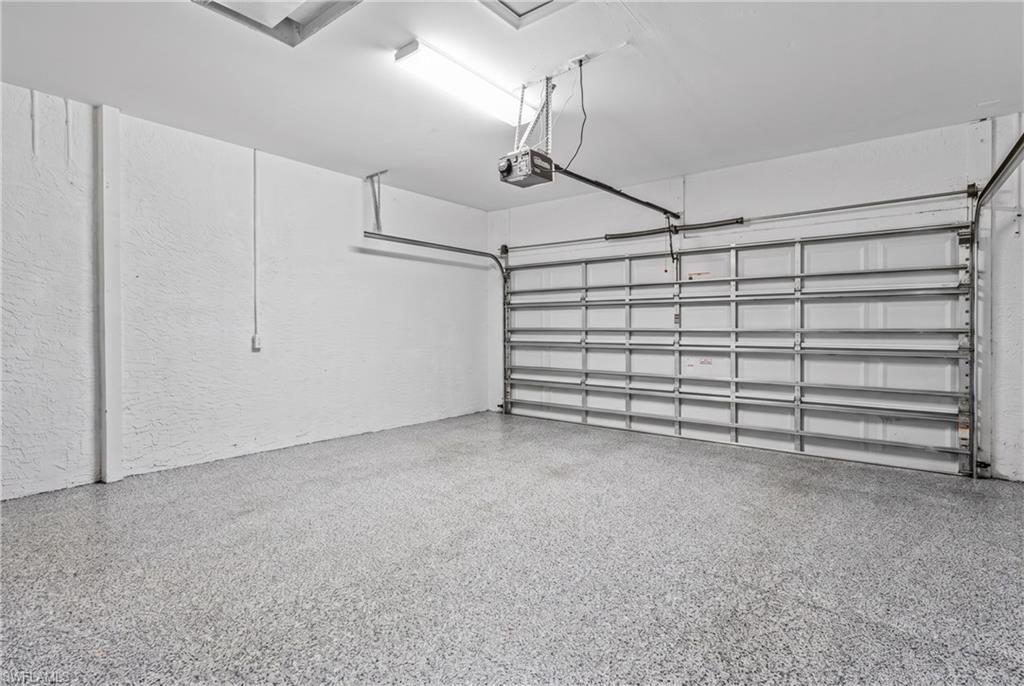 Garage with textured walls, an epoxy floor, and a metal sectional garage door with an automatic opener