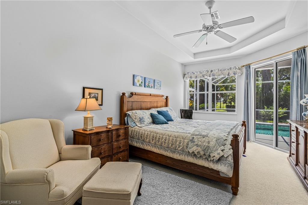 Tray ceiling with a ceiling fan, wall-to-wall carpeting, and a glass sliding door
