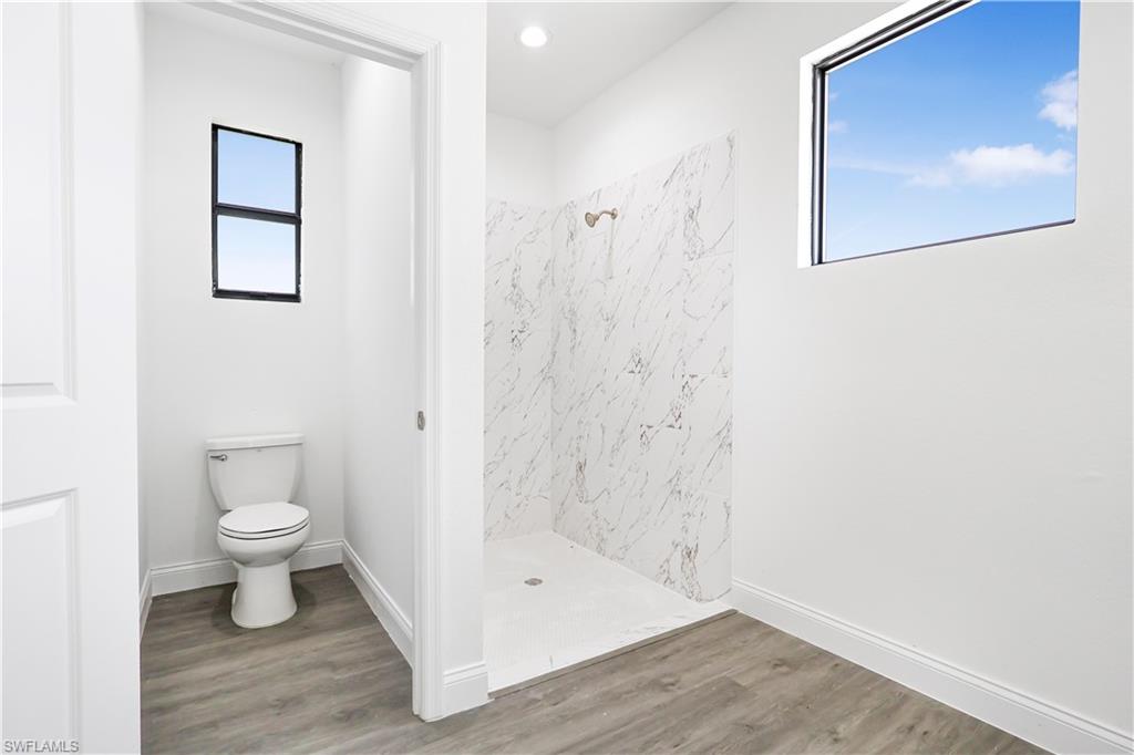 Bathroom featuring a marble finish shower, wood finished floors, and recessed lighting