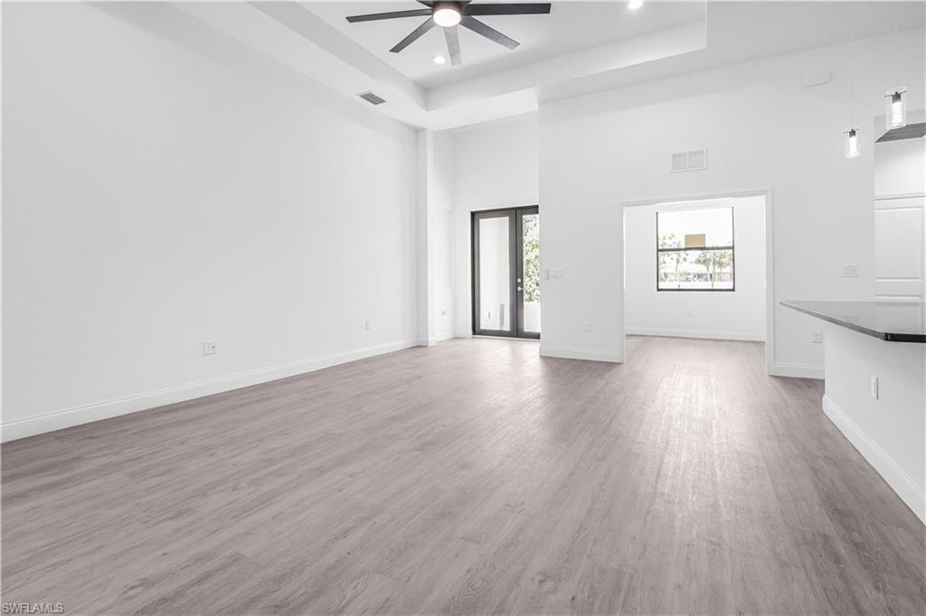 Unfurnished living room with a towering ceiling, light wood finished floors, ceiling fan, and recessed lighting