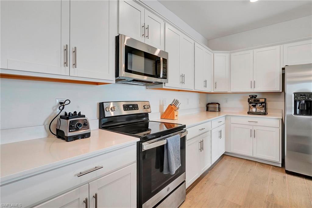 Kitchen with white cabinets, light wood-type flooring, and appliances with stainless steel finishes