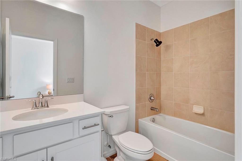 Full bathroom with toilet, tiled shower / bath combo, and vanity