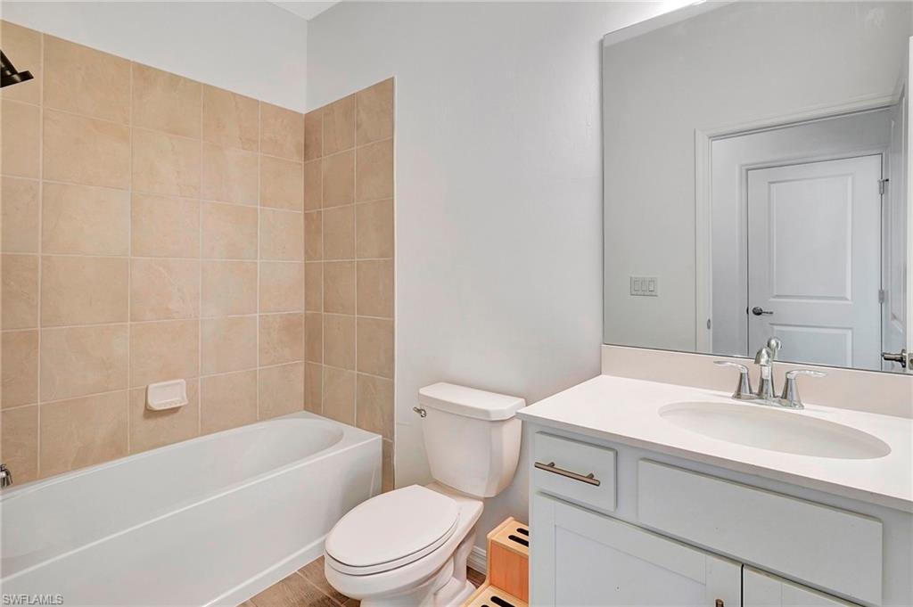 Full bathroom with toilet, tiled shower / bath combo, and vanity