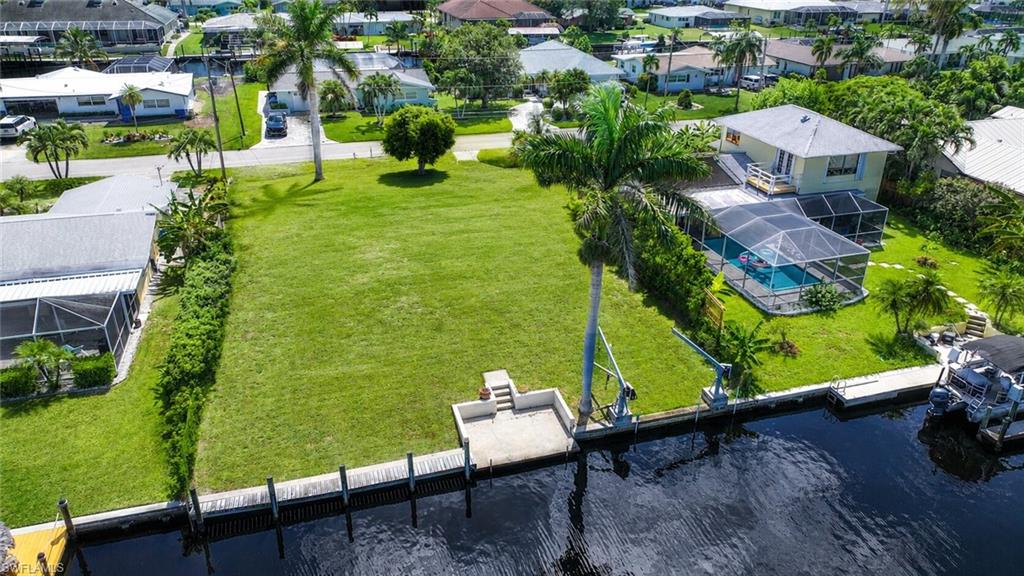Waterfront lot featuring a concrete seawall, boat dock, and lush green lawn
