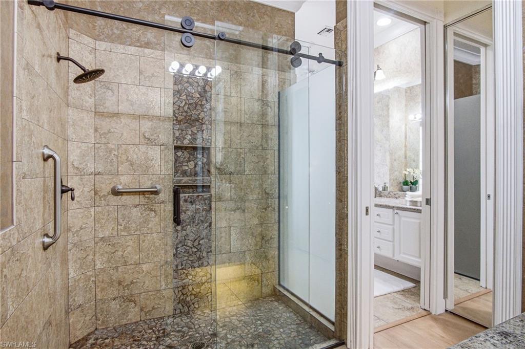 Frameless glass, enclosed shower, separates both toilets and sinks for ultimate primary bedroom bathroom privacy