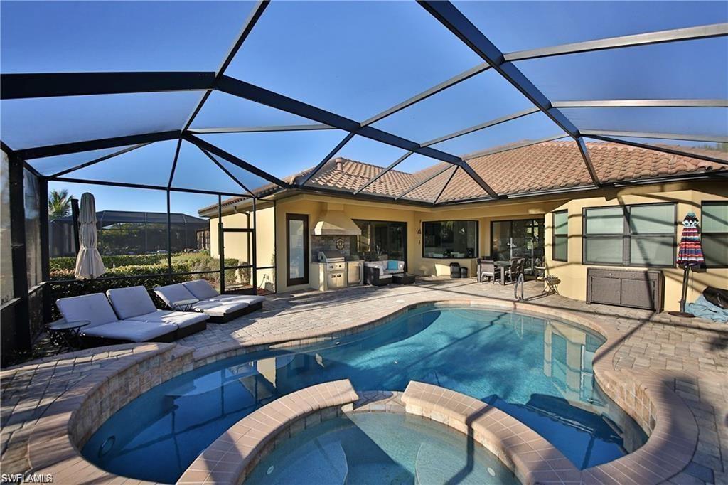 View of swimming pool with a patio, exterior kitchen, glass enclosure, and an in ground hot tub