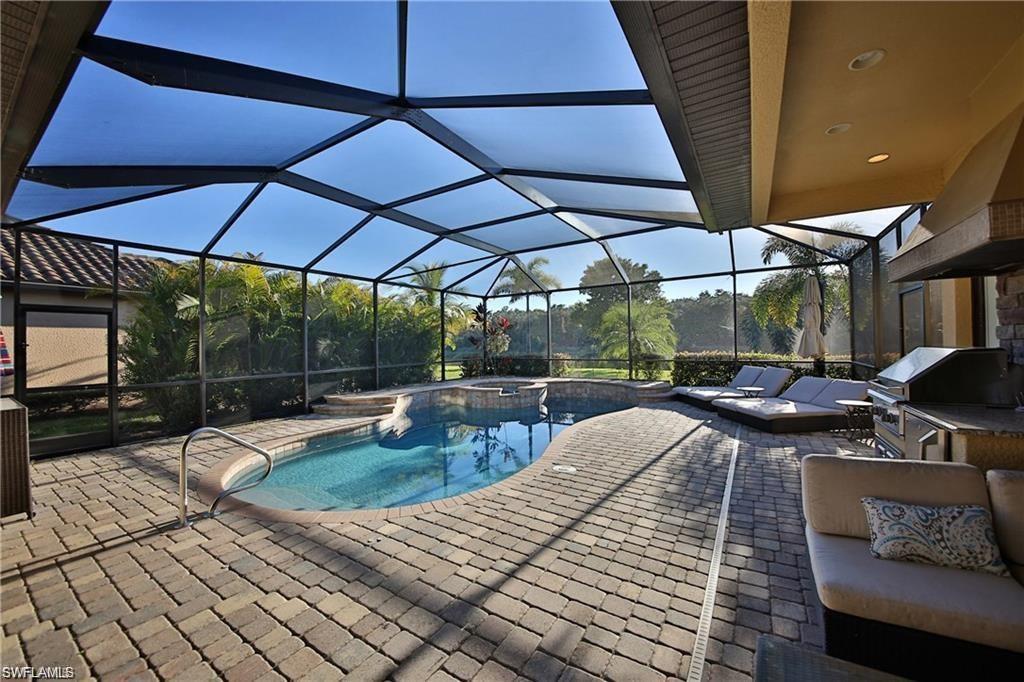 View of pool featuring a patio, exterior kitchen, an in ground hot tub, grilling area, and glass enclosure