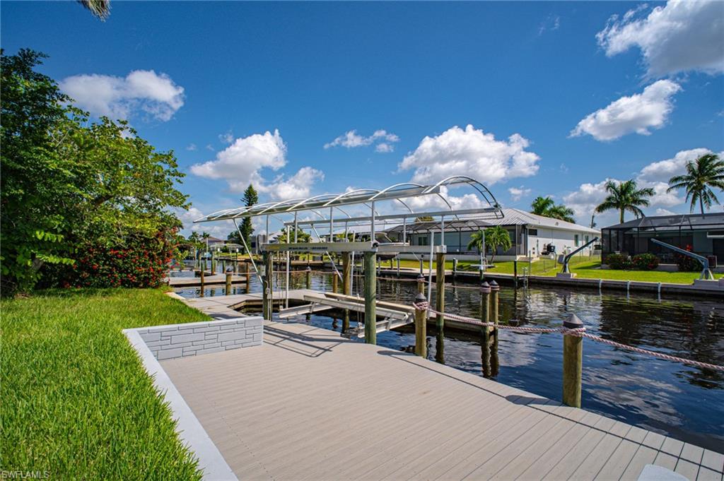 Waterfront dock with a boat lift canopy, composite decking, and a low stacked stone wall