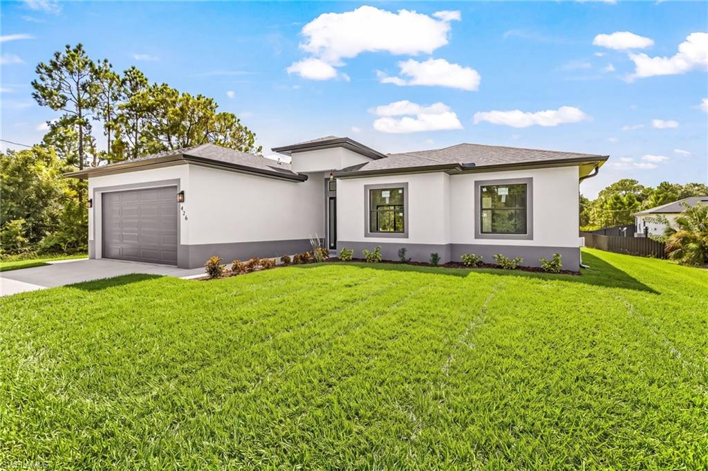 Contemporary stucco exterior with a two-tone finish, dark-framed windows, an attached garage, and a concrete driveway