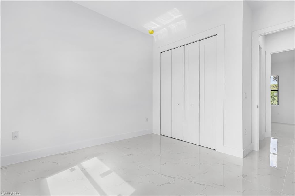 Crisp white walls, bright white tile flooring, and a large bi-fold closet
