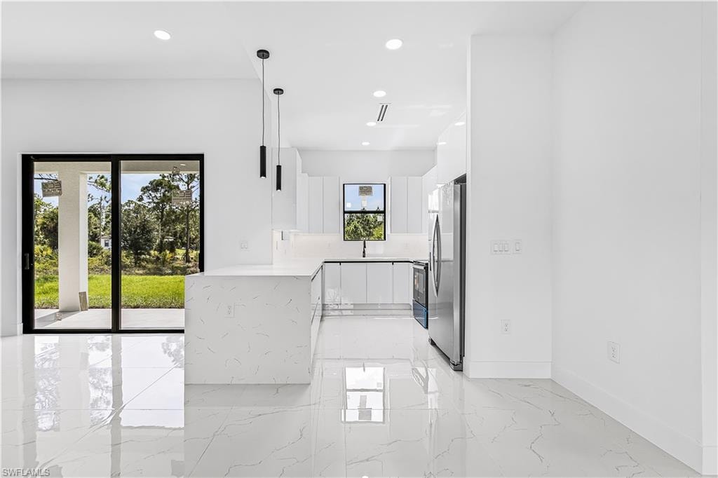 White-finish kitchen cabinetry with integrated appliances, a waterfall island, and recessed lighting