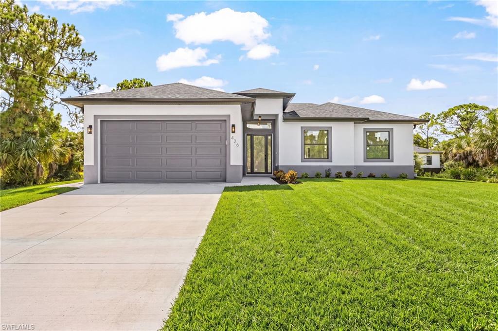 Contemporary facade with a neutral color palette, attached two-car garage, concrete driveway, and front lawn