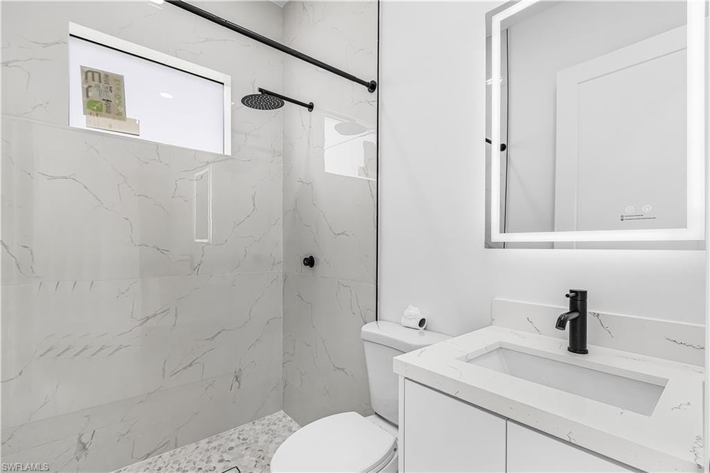 Shower with large format tile walls and pebble-finish flooring