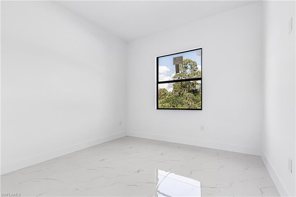 White walls with a single window featuring black trim, complemented by light-colored tile flooring
