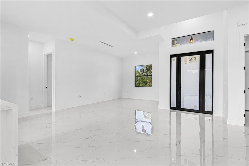 Recessed lighting, glossy tile flooring, transom window, contemporary entry door with sidelights, and a tray ceiling