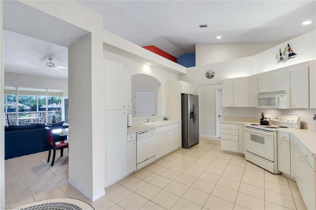 Open Kitchen Featuring White Cabinetry, Light-Toned Tile Flooring, Recessed Lighting, and a Stainless Steel Refrigerator