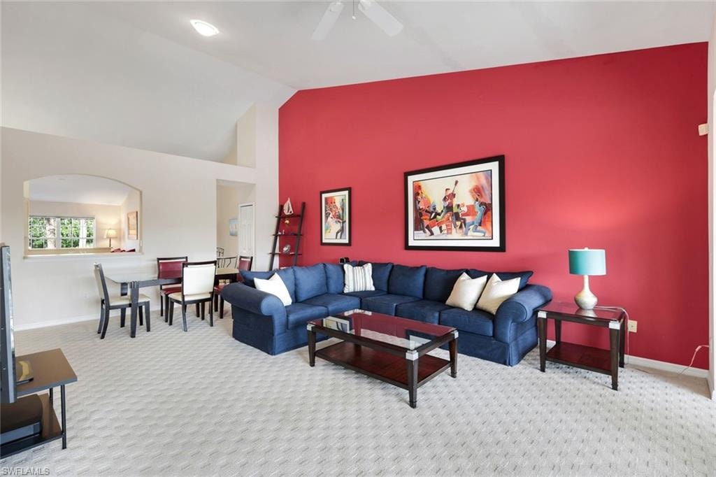 Inviting Living and Dining Areas Featuring a Vaulted Ceiling, Arched Pass-Through, Recessed Lighting, Ceiling Fan, Accent Wall, and Patterned Carpeting