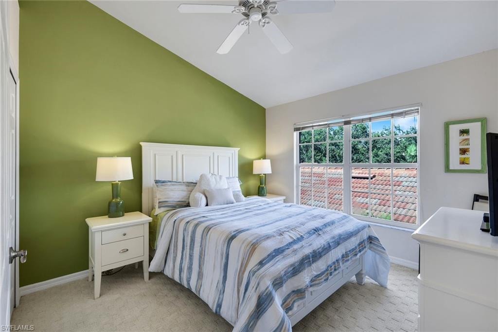 Inviting Guest Bedroom with Vaulted Ceiling, Ceiling Fan, Accent Wall, and Expansive Window