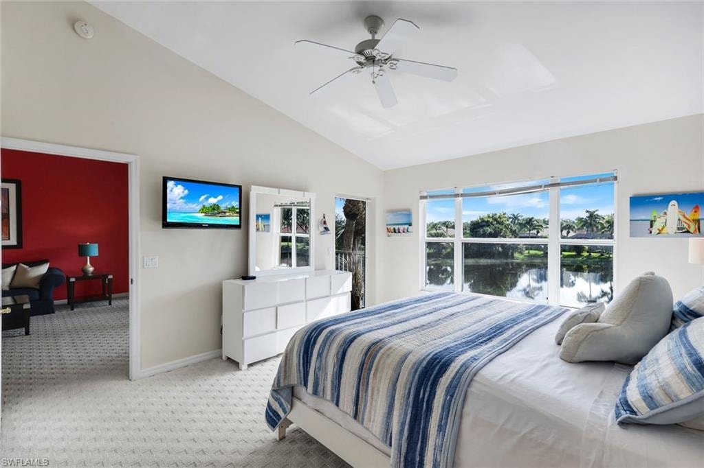 Vaulted ceilings with a ceiling fan, light-colored patterned carpeting, and a wall-mounted television
