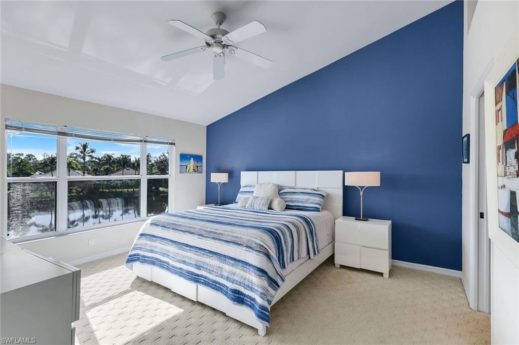 Spacious Primary Suite with Vaulted Ceiling, Ceiling Fan, Accent Wall, Carpeted Flooring, and Expansive Window Overlooking the Lake