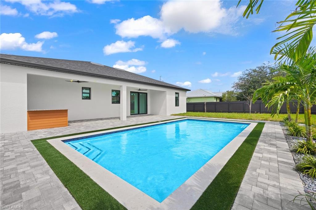 Patio with a rectangular swimming pool, paver hardscaping, and an artificial turf border