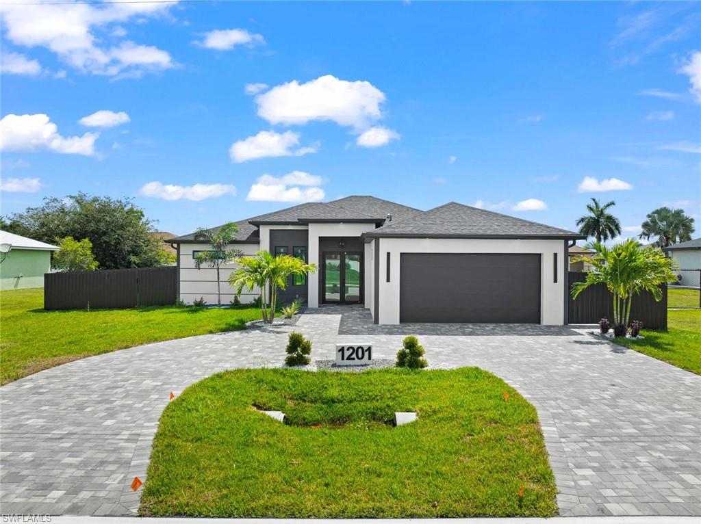 Contemporary exterior with a dark gray garage door, a paved circular driveway, and a white stucco facade