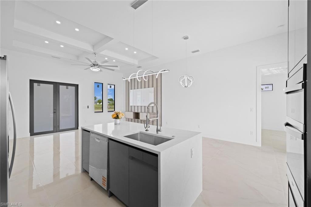 Kitchen island with white countertop, integrated sink, and stainless steel dishwasher