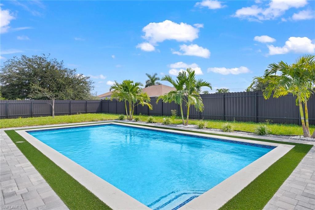 Rectangular swimming pool with tiled steps, surrounded by paver patio and artificial turf accents