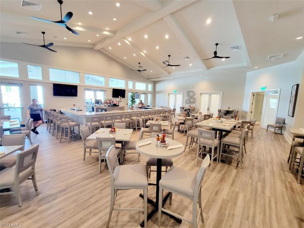 Dining room featuring high vaulted ceiling, ceiling fan, and light hardwood / wood-style floors