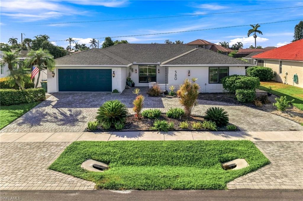 White exterior with dark-framed windows, a dark shingle roof, and a teal garage door