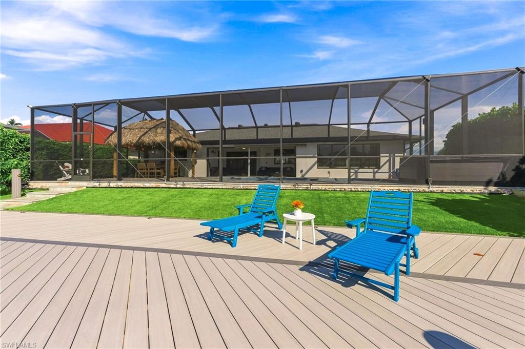 Expansive screened enclosure with a tiki hut, composite wood-finish decking, and manicured lawn