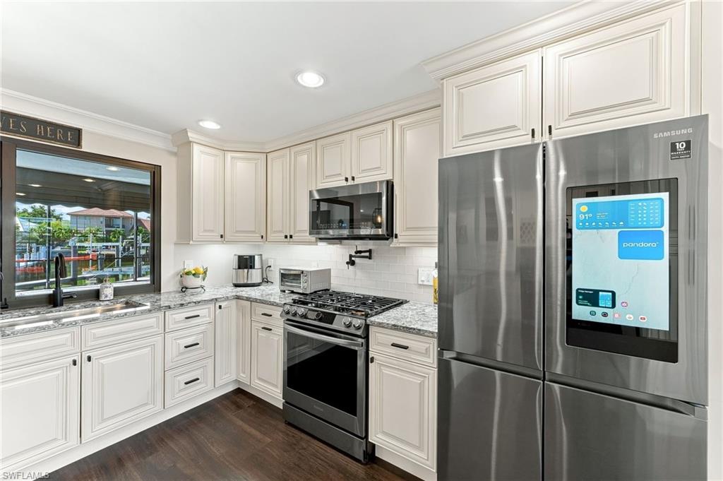 Kitchen featuring white shaker-style cabinetry, stainless steel appliances, granite countertops, and wood-finish flooring