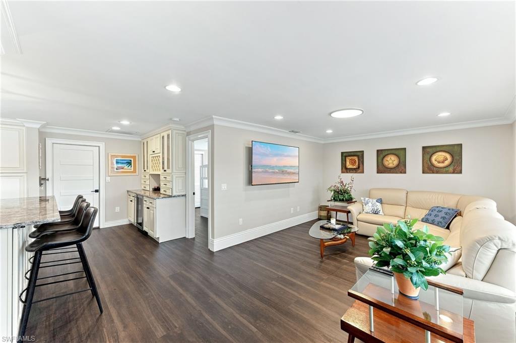 Open concept living area featuring wood-finish flooring, recessed lighting, and crown molding
