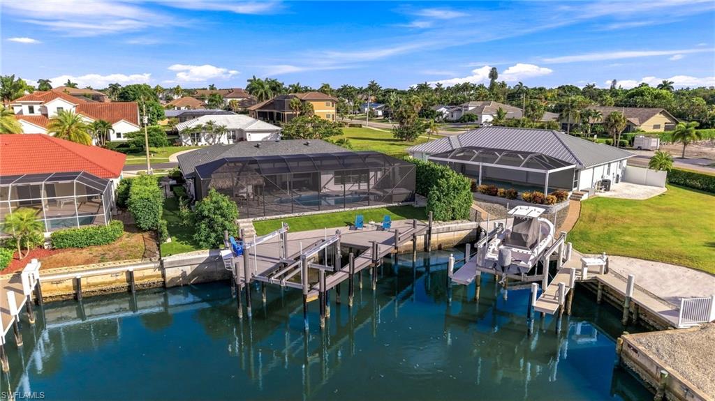 Waterfront property featuring multiple docks, direct water access, and a screened-in pool enclosure