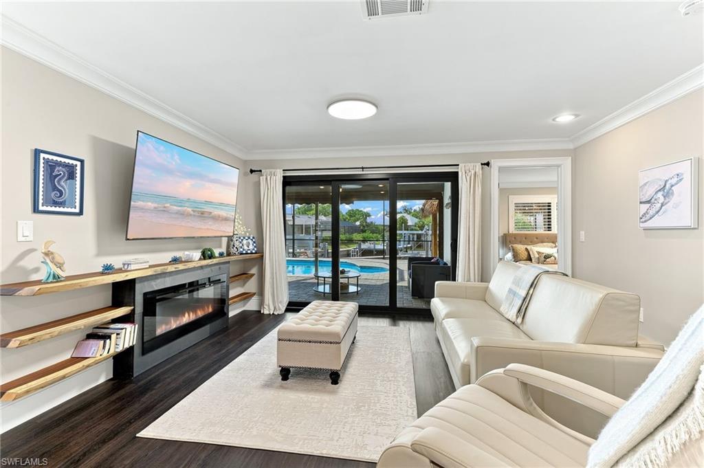 Sophisticated living room featuring dark wood-finish flooring, a linear fireplace with black surround, and recessed ceiling lighting