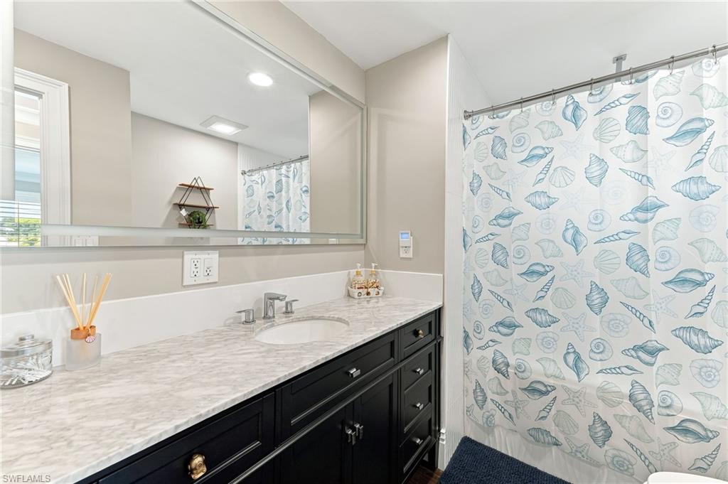 Built-in vanity with a stone countertop, undermount sink, and polished chrome faucet