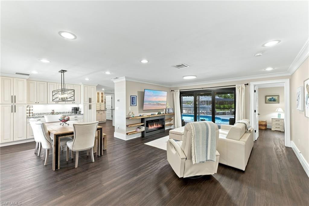 Open-concept living area with dark wood-finish flooring, recessed lighting, and crown molding