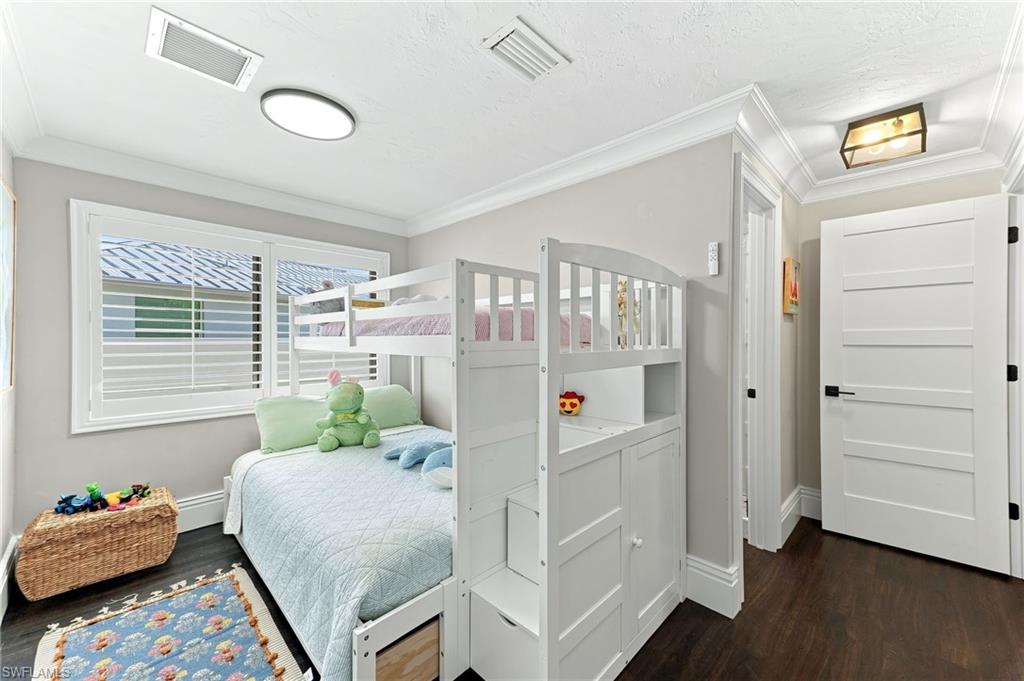 Hardwood-finish flooring, plantation shutters, crown molding, and a modern flush-mount ceiling light