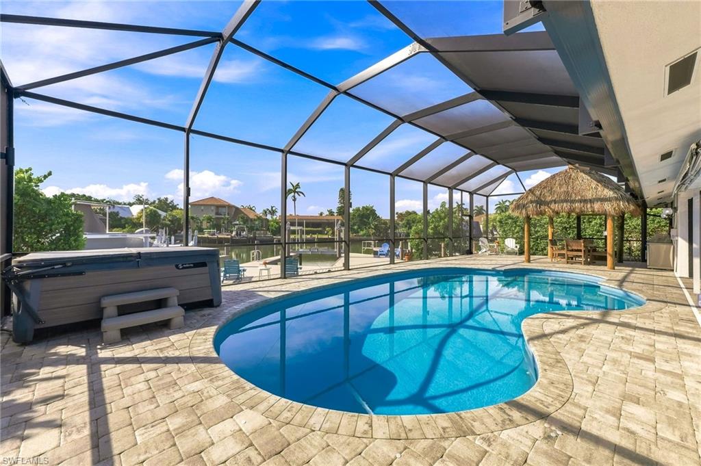 Screened enclosure over a freeform pool, hot tub, and paver patio