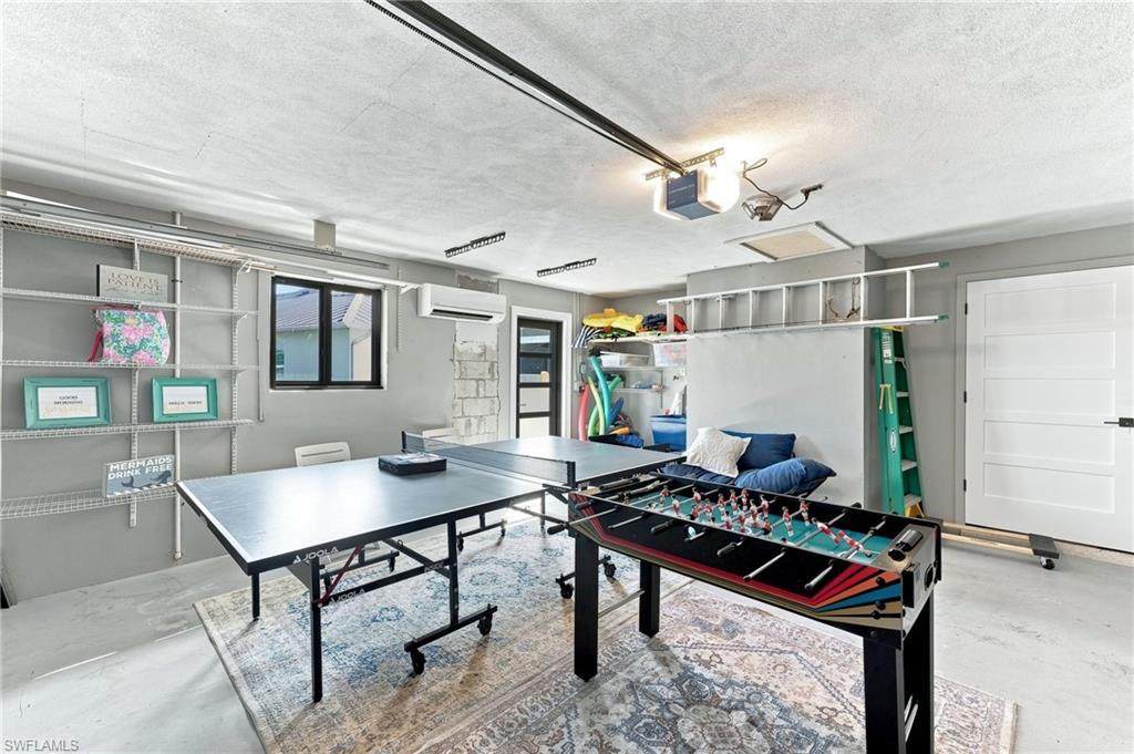 Concrete flooring with area rug, built-in shelving, white paneled interior door, and a wall-mounted AC unit