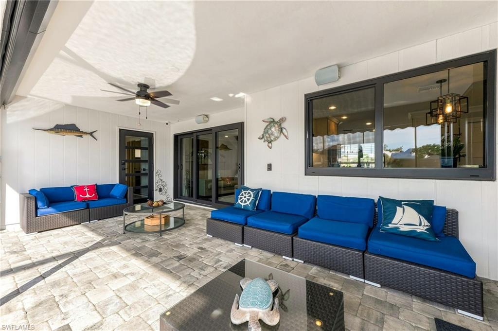 Covered patio with a paver flooring, black-framed sliding glass doors, and a ceiling fan